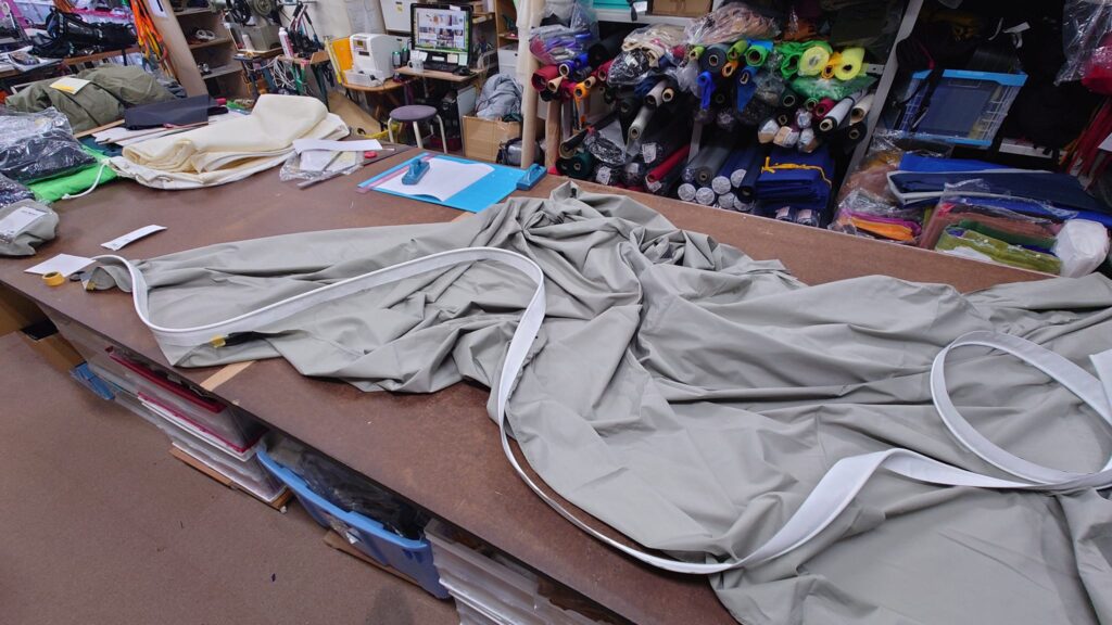 市販製のタープにケダーベルトを裁縫している様子